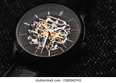 Black male skeleton wrist watch close-up photo. It is a mechanical watch type in which all of the moving parts are visible