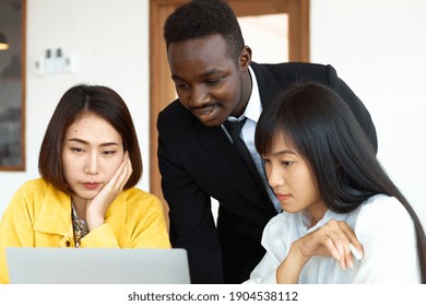 A Black Male Waiter Introducing A Menu To A Young Asian Woman Inside The Restaurant, All Looking At The Front Paper.