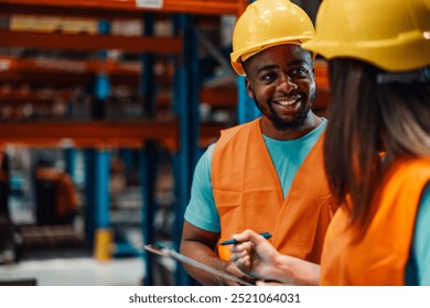 A black male warehouse worker, equipped with essential safety gear, engages in a friendly conversation with his colleague in a bustling industrial area. - Powered by Shutterstock