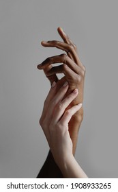 Black Male And White Female Hands Touching Palms Each Other On Gray Background.