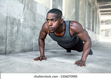 Black male working out alone outside on concrete, pushups in urban downtown city exercise
