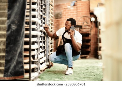 Black man, bakery or phone call with bread trolley for inventory, pastry production or fresh produce at shop. Young African, male person or baker with mobile smartphone for stock check or management - Powered by Shutterstock