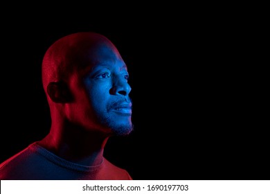 Black Man With Blue And Red Light, Isolated On Black Background, Looking Sideways. Copyspace