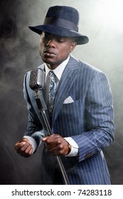 Black Man With Blue Striped Suit And Blue Hat Singing. Smoky Nightclub Like A Cotton Club