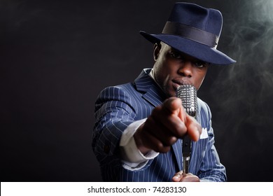 Black Man With Blue Striped Suit And Blue Hat Singing. Smoky Nightclub Like A Cotton Club