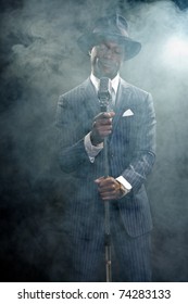 Black Man With Blue Striped Suit And Blue Hat Singing. Smoky Nightclub Like A Cotton Club