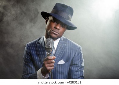 Black Man With Blue Striped Suit And Blue Hat Singing In A Smoky Nightclub Like A Cotton Club