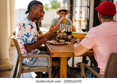 Black Man With Braided Hairstyle Eating At A Table With Friends