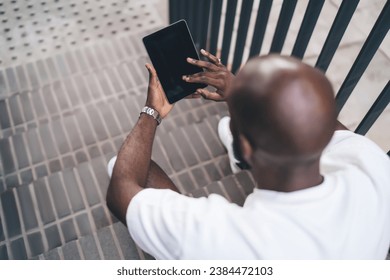 Black man browsing tablet while siting on staircase