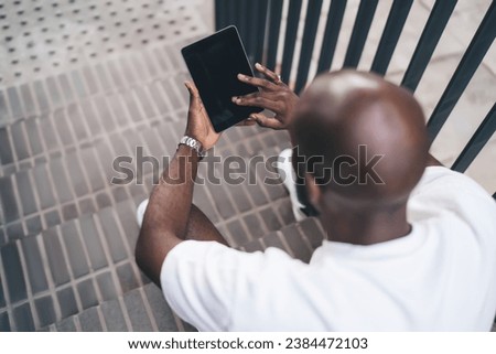 Black man browsing tablet while siting on staircase