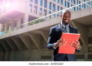 Black Man In A Business Suit Standing Street And Uses Phones And Tablet Computer