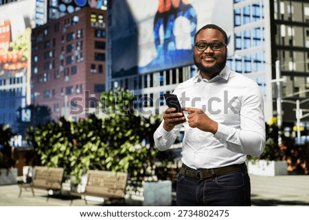 Black man checking apps on mobile phone during walk on downtown street, vibrant energy creating a strong personal presence within busy urbanistic setting near a park. City life.
