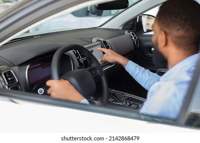 Black Man Choosing New Car In Auto Salon, African American Male Customer Sitting Inside Of Automobile And Touching Multimedia Screen While Purchasing Vehicle In Modern Dealership Center, Closeup