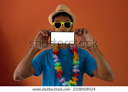 Black man in costume for brazil carnival holding blank mobile next to the mouth isolated on orange background. 
