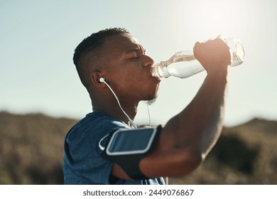 Black man, drink water and music in outdoors for running, thirst and hydrate on sports break. Person, profile and mineral liquid in bottle for nutrition, athlete and phone app for streaming song - Powered by Shutterstock