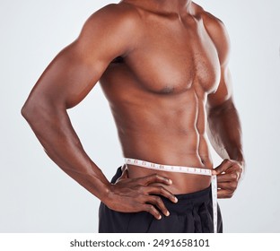 Black man, fitness and waist with measuring tape for weightloss, diet or slimline on a gray studio background. Muscular African, male person or model with body measurement for wasitline, size or BMI - Powered by Shutterstock