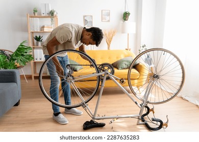 Black man fixing bicycle on floor - Powered by Shutterstock