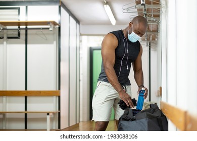 Black Man Getting Ready In The Gym Locker Room. He Is Wearing A Medical Mask. New Normal Concept.