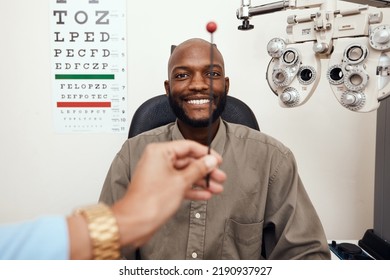 Black Man Having His Eyes Tested At An Optometrist. Smiling African American Male Consulting With An Opthamologist, Having A Vision And Eye Care Checkup. Guy Testing For Glaucoma Or Myopia