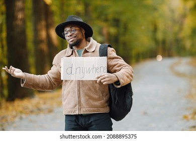Black man hitchhiking on a road and holding a sign anywhere