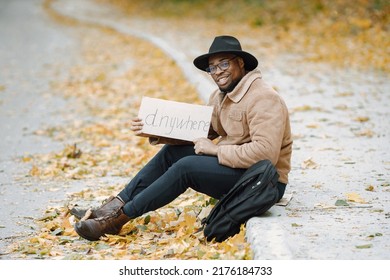 Black man hitchhiking on a road and holding a sign anywhere