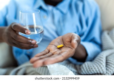 Black man hold pills and jar in his hands. Concept of healthcare and medicine, patient take daily dose of prescribed medicament, feel sick, antibiotics, painkillers or antidepressants. Close up - Shutterstock ID 2132999459