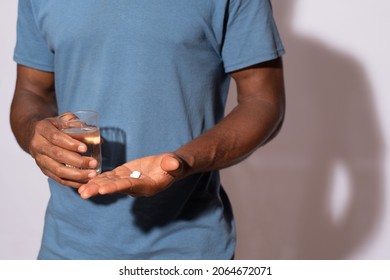 Black Man Holding A Glass Of Water And Medication