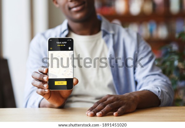 Black man holding smartphone with opened taxi\
services mobile app on screen, african american guy showing new\
mobile application for cab ordering, sitting at table in cafe,\
creative collage
