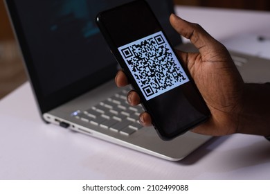 A Black Man Holding A Smartphone With A QR Code On The Screen