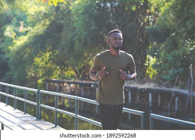 Black Man Jogging And Running Beside Road In Park At Autumn Morning. 