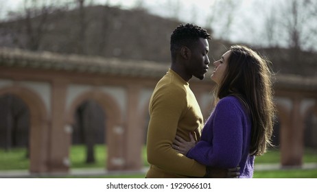 
Black Man Kissing White Girlfriend Standing Outside At Park