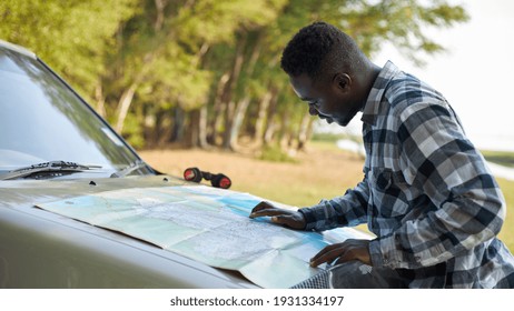 A Black Man Was Looking At A Map To Find A Route In Front Of The Car.