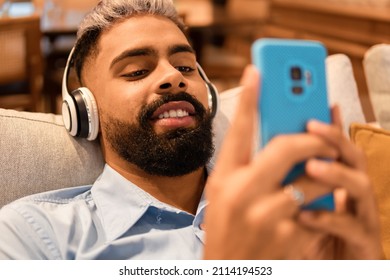 Black Man Lying And Looking At Mobile Phone And Watching Video In The Couch