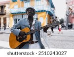 Black Man musician playing guitar on the street in La Havana Cuba in Latin America Caribbean city