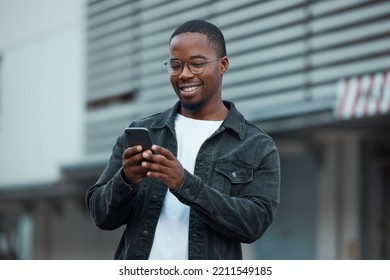 Black man, phone and social media in city reading text message or communication on social network app. African American person, chat conversation and happy on 5g mobile smartphone in Atlanta smile - Powered by Shutterstock