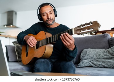 Black Man Playing The Guitar At Home And Using A Laptop