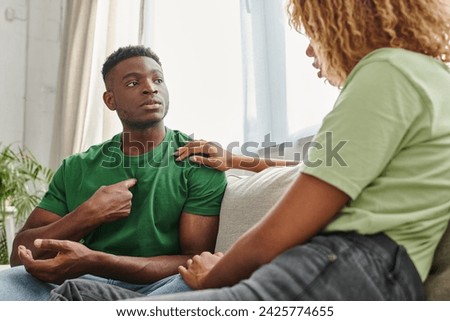 black man pointing at himself while communicating with girlfriend and using sign language