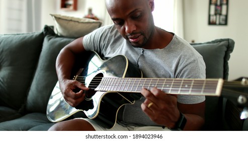 Black Man Practicing Guitar At Home. African Mixed Race Learning To Play Musical Instrument