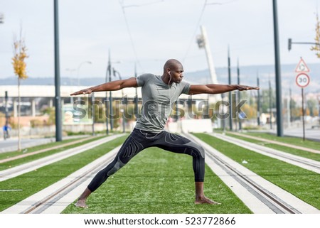 Black man practicing yoga in urban background.