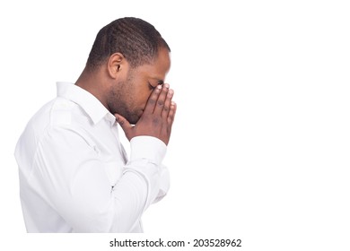 black man praying and standing facing right. Man dressed in white shirt closed eyes