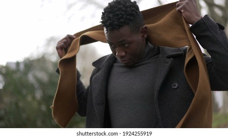 Black Man Putting Scarf Outdoors In Winter Season. African Guy Adjusting Scaf In The Cold Wearing Coat