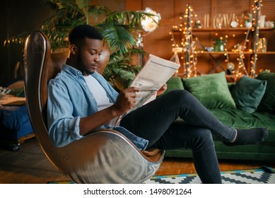 Black Man Reading Newspaper In A Comfortable Chair