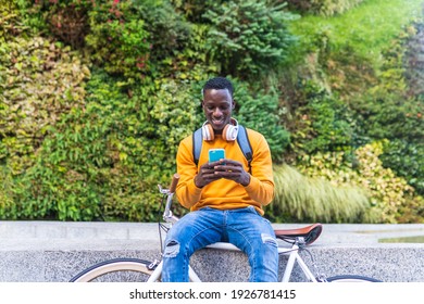 Black Man Riding Bike Using Cellphone Outdoors. African American Young Man Using Phone In The City. Lifestyle Concept.