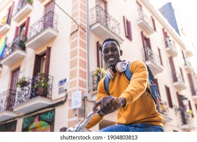 Black Man Riding Bike Wearing Yellow Sweater Outdoors. African American Young Man Riding Bike In The City. Lifestyle Concept.