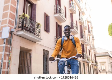 Black Man Riding Bike Wearing Yellow Sweater Outdoors. African American Young Man Riding Bike In The City. Lifestyle Concept.