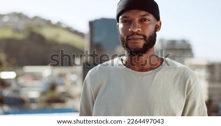 Black man, serious and portrait on rooftop in city, wind or confident in summer on holiday. Young, man and buildings in urban, metro or town with proud, sunshine and beard with focus, vision or dream