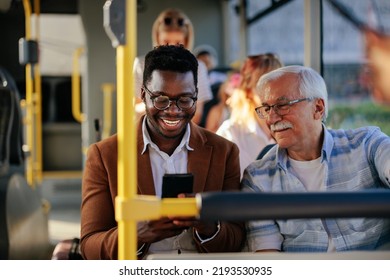 Black man is showing a caucasian senior man his smartphone on the public transport