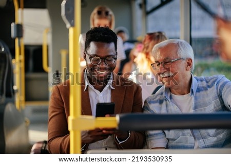 Black man is showing a caucasian senior man his smartphone on the public transport Foto stock © 