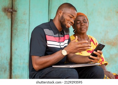 Black Man Showing An Old African Woman Content On His Phone