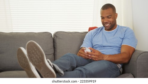 Black Man Sitting On Couch Texting